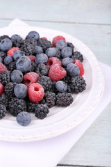 Iced berries on plate, on color wooden background