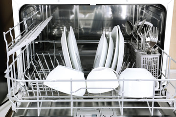 Open dishwasher with clean utensils in it