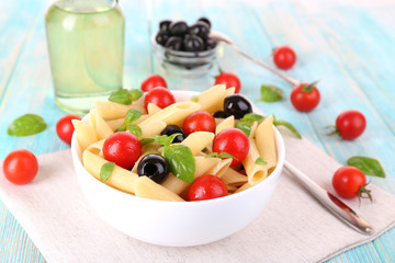 Pasta with tomatoes, olives and basil leaves in bowl