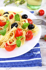 Spaghetti with tomatoes, olives and basil leaves