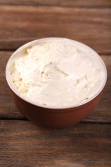 Fresh homemade butter in bowl, on wooden background