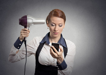 woman reading news on smartphone holding hairdryer