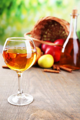 Apple cider in wine glass and bottle, with cinnamon sticks and