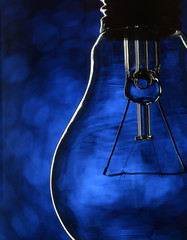 Closeup of a glass incandescent tungsten bulb on blue background