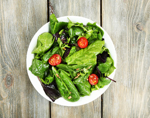 Fresh green salad in bowl on wooden table