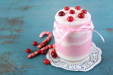 Raspberry milk dessert in glass jar, on color wooden background