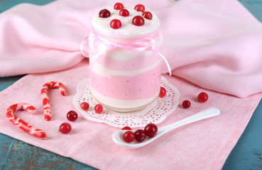 Raspberry milk dessert in glass jar, on color wooden background