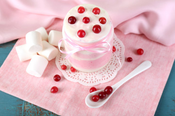 Raspberry milk dessert in glass jar, on color wooden background