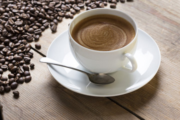 Cup of coffee with foam in a white cup with beans