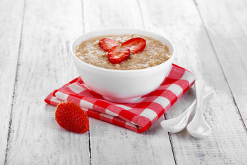 Tasty oatmeal with strawberry on table close-up