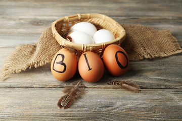Eggs with inscription BIO on eggshell, on wooden background