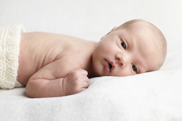 Newborn baby boy lying on white in studio