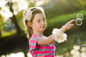 Cute girl chasing soap bubbles