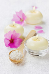 spa composition with sea salt, pink flowers and burning candles