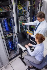 Team of technicians using digital cable analyser on servers