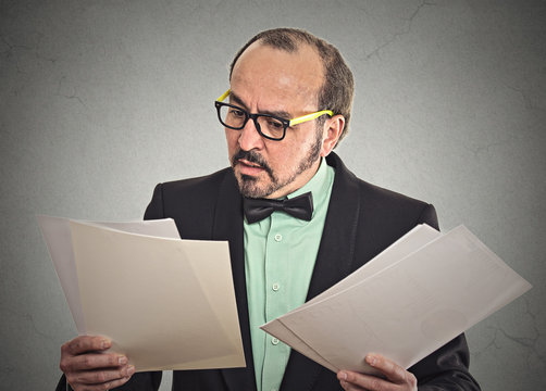Confused businessman looking at documents papers contracts