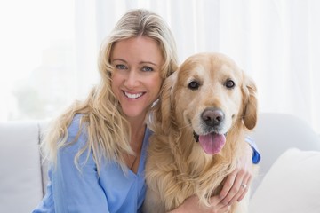 Smiling blonde woman hugging her golden retriever