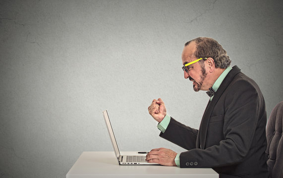 man angry frustrated at computer grey wall office background 