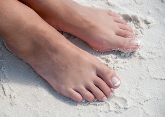 Relaxing at a beach, with beautiful woman feet in the warm sand