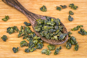 Green tea in a wooden spoon on a wooden board