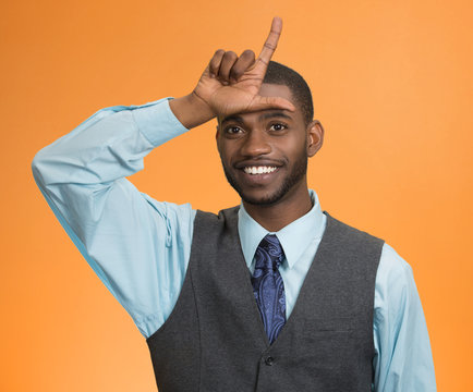 man showing loser sign on forehead isolated on orange background