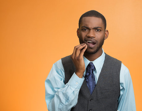 Man with toothache touching face isolated on orange background 