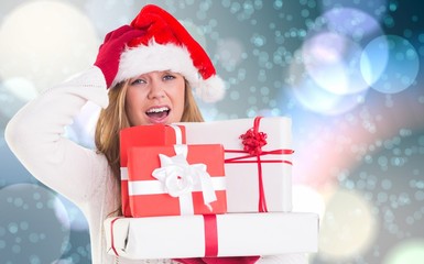 Composite image of festive blonde holding pile of gifts