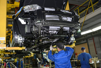 Workers on the assembly conveyor of automobile plant