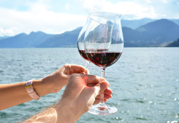 Two wineglasses in the hands against lake Como, Italy
