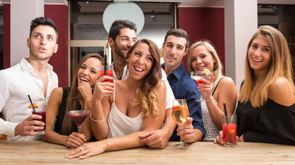 Young friends having fun in a bar drinking cocktail.