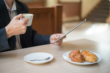 Man with tablet computer reading news at motning in cafe