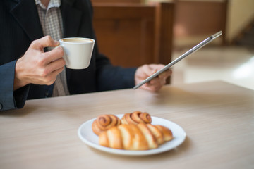 Man with tablet computer reading news at motning in cafe