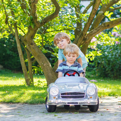 Two happy twin boys playing with toy car