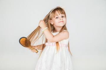 Smiling little girl brushing her hair closeup