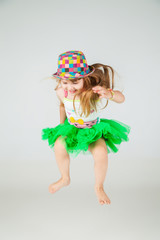 girl in green dress and hat jumps on white