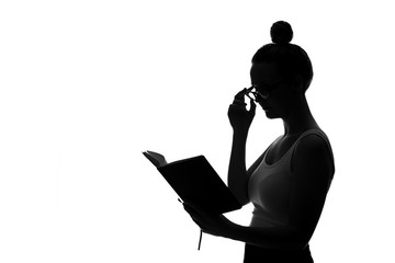 Silhouette of young woman reading book against white background