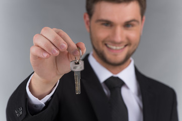 Businessman in tie holding key with focus on key.