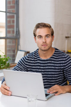 junger mann mit laptop in seinem apartment