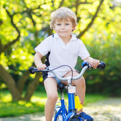 Fototapeta na wymiar Happy preschool kid boy having fun with riding his bicycle