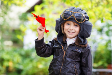 Fototapeta na wymiar Happy kid in pilot helmet playing with toy airplane