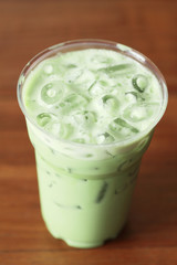 glass of milky green tea on wooden background
