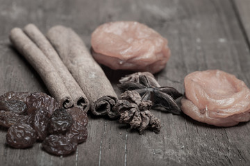 Raisins, cinnamon, anise and dried apricots lying on an old wood