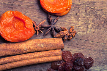 Raisins, cinnamon, anise and dried apricots lying on an old wood