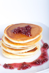 Pancakes with raspberry jam on a light background