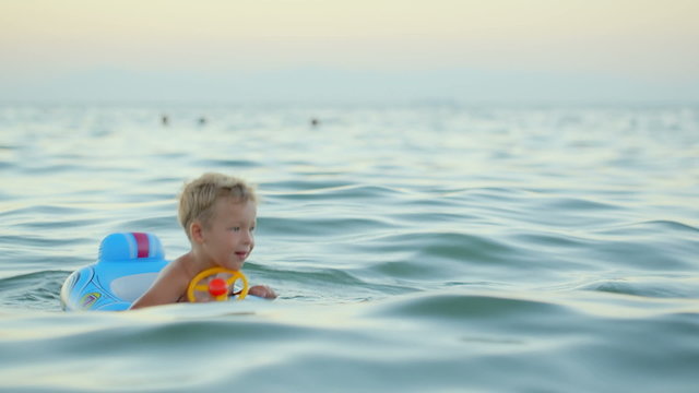 Boy with rubber ring swimming in sea
