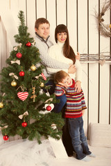 parents and kid near Christmas tree.