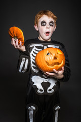 red haired child in Halloween costume holding a orange pumpkin