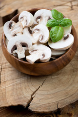 Close-up of sliced champignons in a wooden bowl, vertical shot