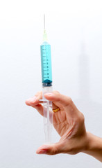 Blue vaccine in syringes on right hand.