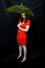 girl wearing red dress stands under an umbrella